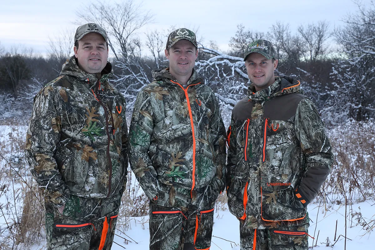 The three Beasley brothers standing in a snowy field in camouflage